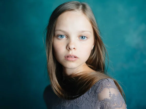 모델의 모습을 클로즈업 한 푸른 배경 위에 회색 드레스를 입은 아름다운 어린 소녀의 모습 — 스톡 사진