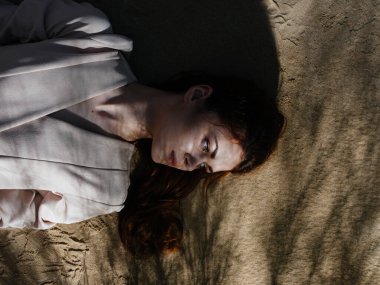 Kadın kumlara uzanıp yaz güneşini dinlendiriyor.