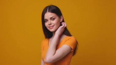 Flört eden kadın saçlarını düzeltiyor gülümsüyor ve kameraya bakıyor, stüdyoya.