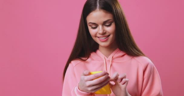 Kvinna tittar på telefonen ler och kommunicerar, rosa bakgrund — Stockvideo