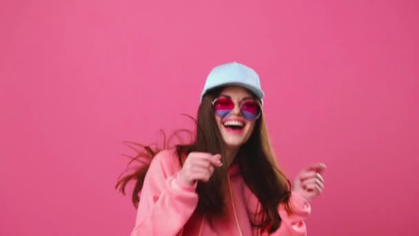 Mulher feliz com um belo sorriso dançando e pulando em um fundo rosa, emoções positivas — Vídeo de Stock