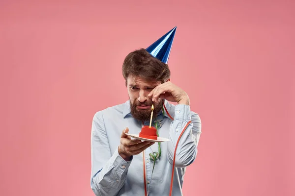 Cumpleaños de un hombre con un pastel y con una vela sobre un fondo rosa — Foto de Stock