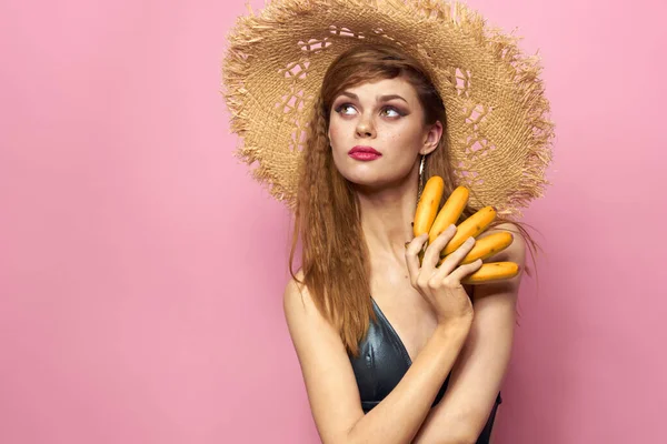 Kvinna i stranden halm hatt bananer håller frukt Exotisk baddräkt rosa bakgrund — Stockfoto