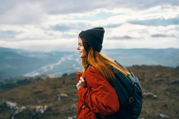 Mulher viaja nas montanhas paisagem mochila casaco vermelho e chapéu modelo — Fotografia de Stock