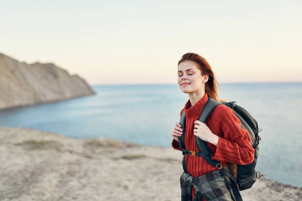 Bella donna con uno zaino in montagna maglione rosso modello acconciatura oceano mare — Foto Stock