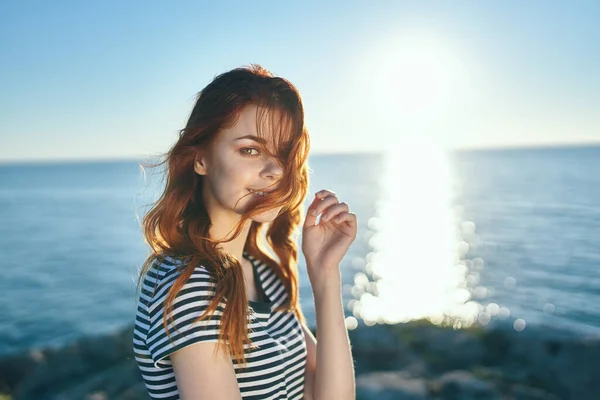 Donna dai capelli rossi in t-shirt vicino al mare al tramonto in montagna nella natura — Foto Stock