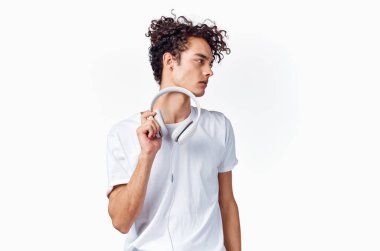 Kulaklık takan yeni teknolojili beyaz tişört giyen bir genç. Arka plan müzik modeli.