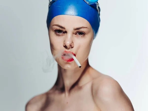 Una mujer con una gorra azul con un cigarrillo en los dientes y maquillaje brillante — Foto de Stock