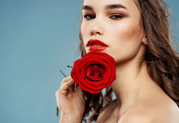 Sexy vrouw met ontbloot schouders en een rode bloem in de buurt van het gezicht — Stockfoto