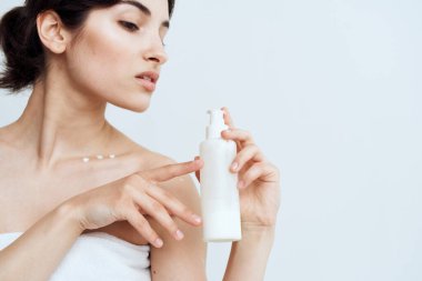 Güzel esmer, çıplak omuzlu, el kremi sürmüş, cilt bakımı yaptırmış.