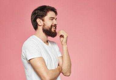 Kafası karışmış, elleri yana bakan, pembe arka planı olan bir adam.