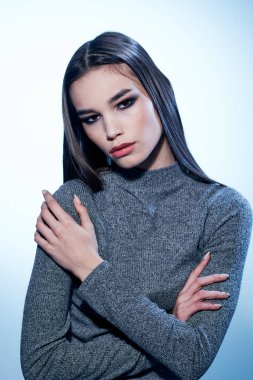 Çekici bir kadının portresi açık arkaplanda gri bir süveter ve yakın plan yüzünde makyaj.