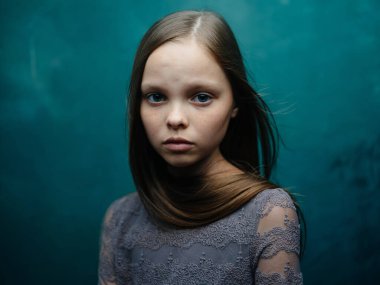 Gri elbiseli güzel bir kızın portresi ve turkuaz arka planda sarı saçlar.