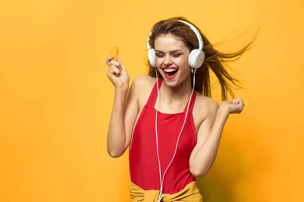 Mulher emocional em fones de ouvido brancos escuta música divertida estilo de vida fundo amarelo — Fotografia de Stock