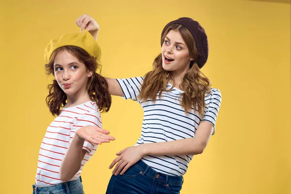 funny mom and daughter wearing hats fashion fun joy family yellow background