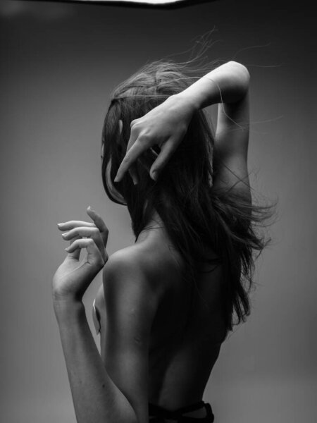 Back view of nude woman with loose hair in black and white photograph. High quality photo