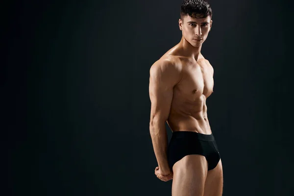 Atractivo hombre deportivo en pantalones cortos oscuros fase Studio fondo oscuro — Foto de Stock
