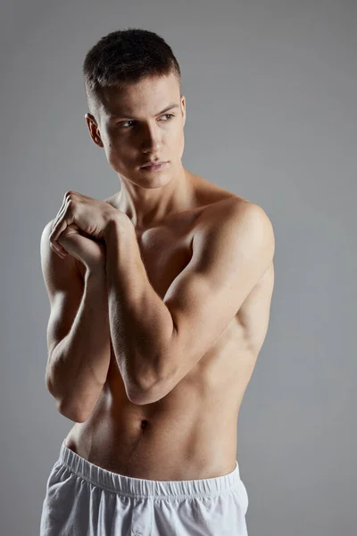 Guy with athletic physique joined hands near shoulder on gray background cropped view — Stock Photo, Image