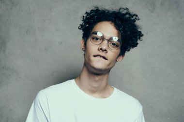 Gözlüklü, kıvırcık saçlı, beyaz tişörtlü stüdyo duyguları olan adam.