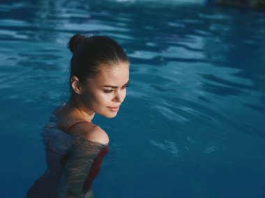 Havuzda mayo giymiş bir kadın lüks içinde yüzüyor.