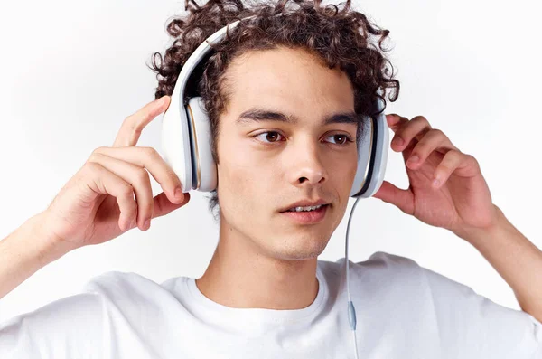 Man med lockigt hår och i hörlurar lyssnar på musik — Stockfoto