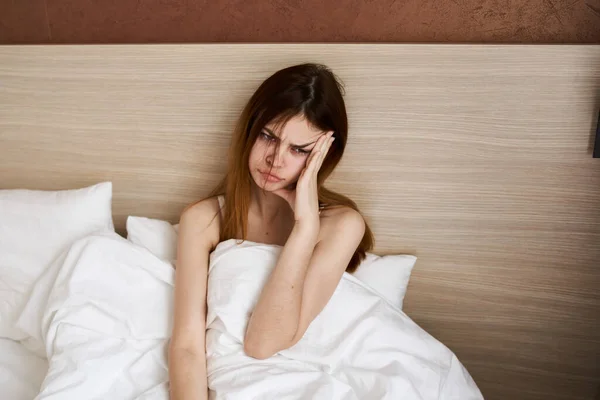 upset woman woke up early in the morning in bed under a white blanket