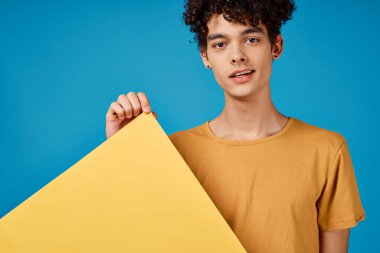 Sarı tişörtlü adam afiş modeli, mavi arka plan reklamı.