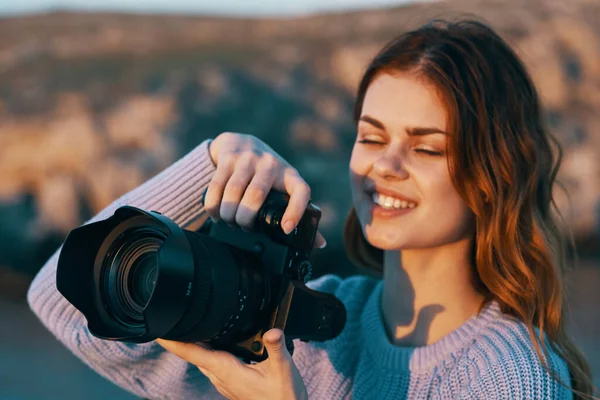 Szczęśliwa kobieta fotograf z aparatem fotograficznym w górach na łonie natury i rzeki w tle — Zdjęcie stockowe