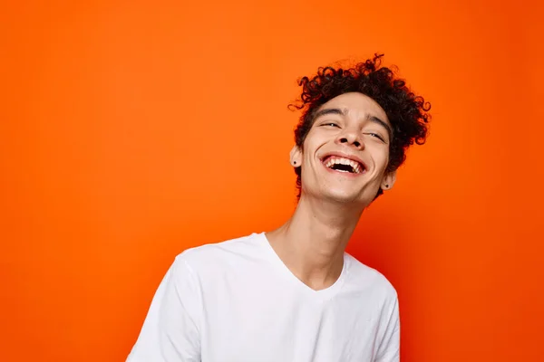 Junger Mann in weißem T-Shirt lockiges Haar Lächeln orange Hintergrund — Stockfoto