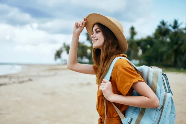 Mulher viaja na praia perto do mar com uma mochila nas costas — Fotografia de Stock