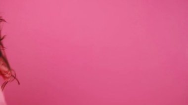 Pembe arka planda koşan genç ve güzel bir kadın.