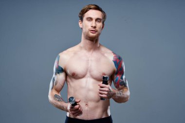 Karnında küpler olan erkek sporcu çıplak gövde dövmesi yapan vücut geliştiriciler spor yapıyor.