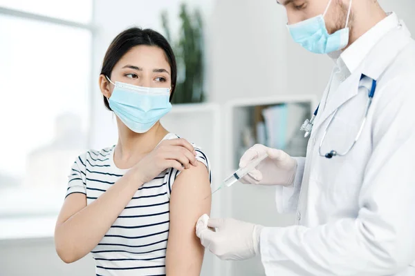 En läkare injicerar ett vaccin till en kvinnlig patient som — Stockfoto