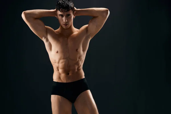 Atractivo deportista hombre con bombeado hasta abdominales posando en oscuro estudio bragas — Foto de Stock