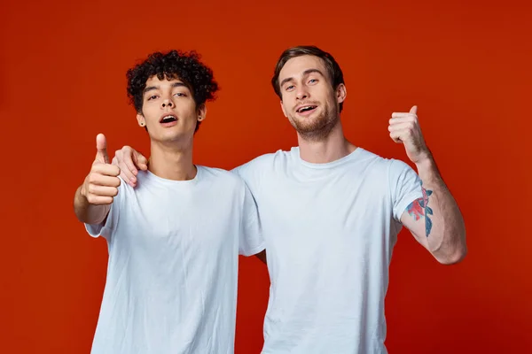 Dos hombre en blanco camisetas divertido emociones mano gestos amistad abrazos — Foto de Stock