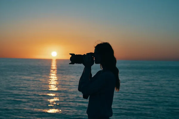 海の近くの日没時にカメラを持った写真家が — ストック写真