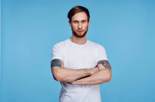Stilig man i vit t-shirt tatueringar på armarna beskärd vy blå bakgrund — Stockfoto