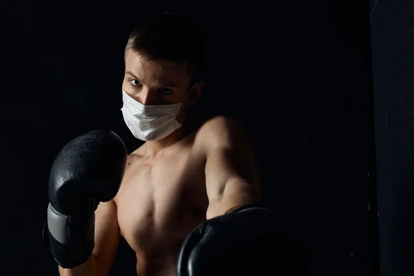 Боксер в медицинской маске и боксерских перчатках на черном фоне — стоковое фото