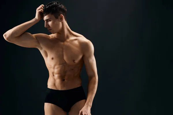 Привабливий чоловічий спортсмен у темних шортах м'язи позують ізольований фон — стокове фото