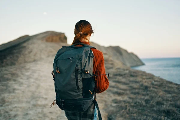 Bella donna che viaggia in montagna con uno zaino sulle spalle vicino al mare — Foto Stock