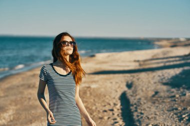 Doğada yaz mevsiminde deniz kenarında yürüyen bir kadın.