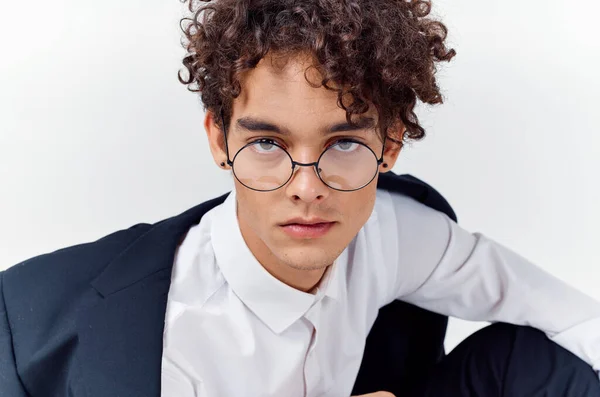 Portrait of a curly-haired guy in a shirt in a jacket and glasses on a light background close-up — Stock Photo, Image
