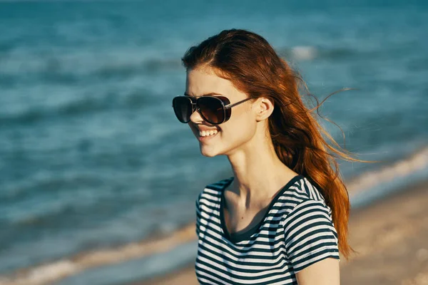 Radosna kobieta w koszulce i okularach spoczywa na brzegu morza w górach — Zdjęcie stockowe