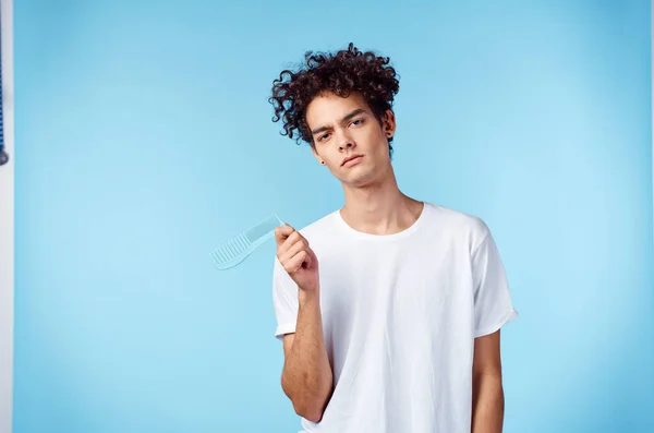 Chico en camiseta blanca pelo rizado teléfono en manos tecnología fondo azul — Foto de Stock