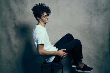 Sandalyede oturan sevimli adam kıvırcık saçlı, gülümseyen yaşam tarzı.