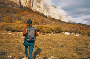 Kadın sonbaharda doğada dinleniyor dağlarda mavi gökyüzü manzarası sırt çantası