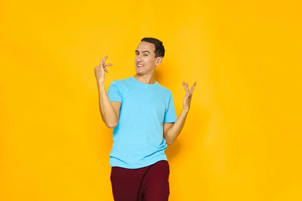 Homem azul t-shirt gestos com as mãos emoções amarelo fundo — Fotografia de Stock