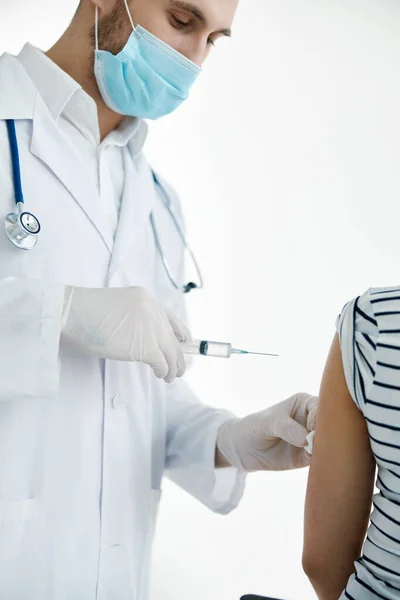 Médico masculino em um casaco branco injeções no braço com uma vacina coronavírus — Fotografia de Stock
