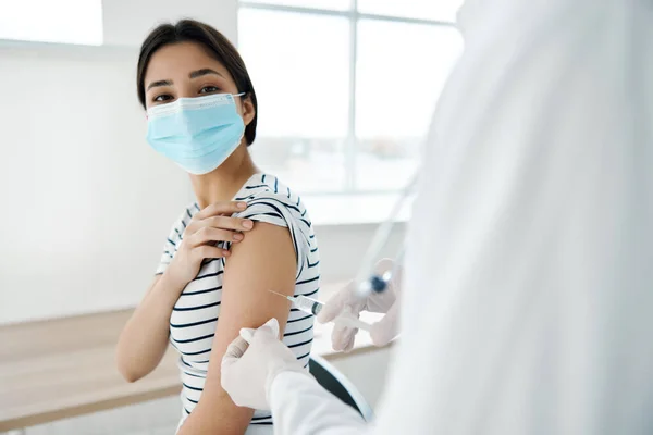 一名身穿白衣的医生在一名妇女病人的肩上注射疫苗 — 图库照片