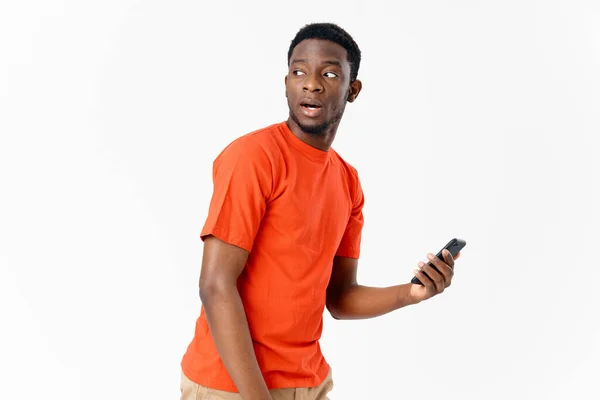 Homem africano tshirt laranja telefone celular luz fundo — Fotografia de Stock